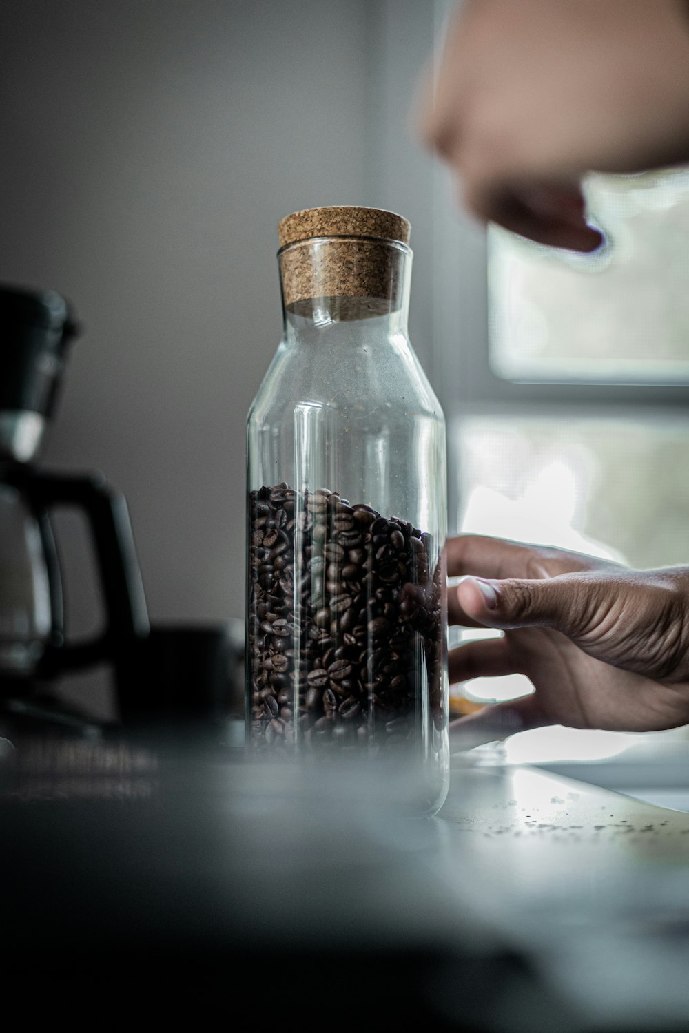 a person putting coffee beans in a glass jar