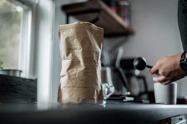 A smiling customer holding a bag of Argaeos Coffee beans in a cozy kitchen setting.