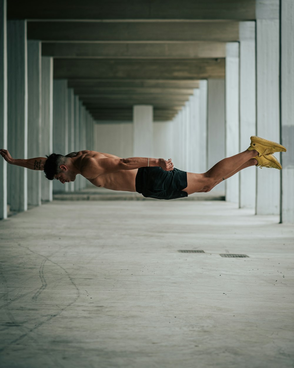 a shirtless man is diving in a parking garage