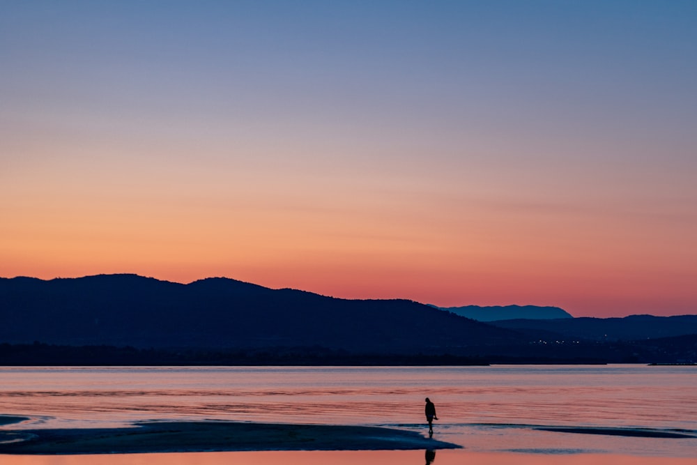 a person standing on a beach at sunset