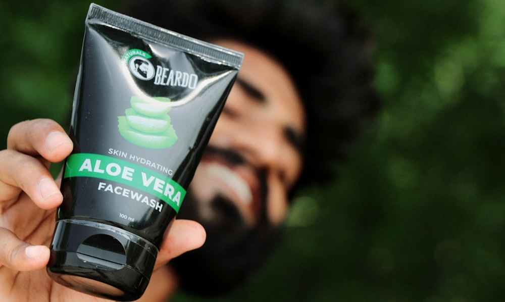 a man holding a tube of aloe vera face wash