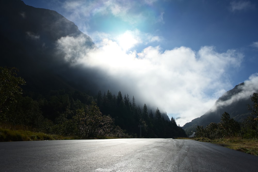 the sun shines through the clouds on a mountain road