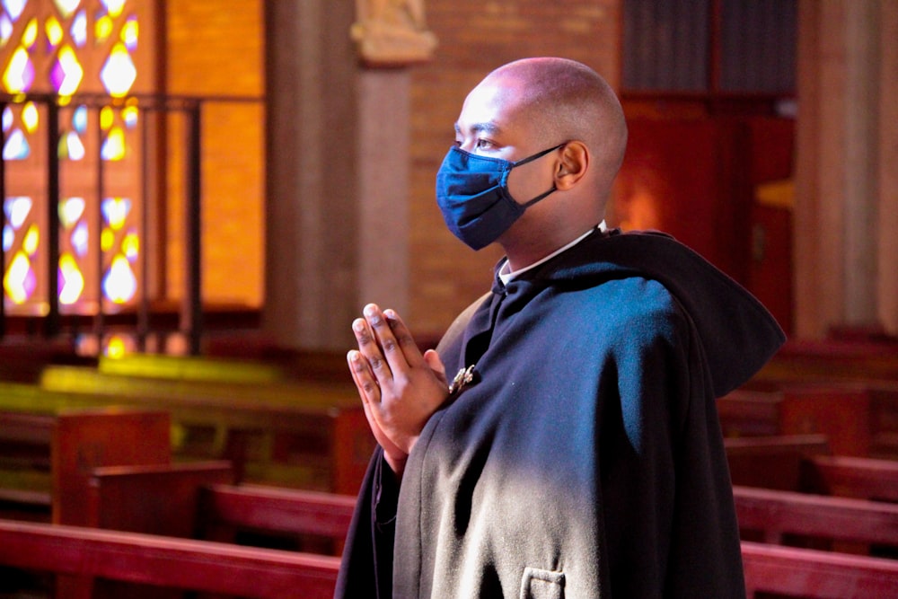 a man wearing a face mask and praying in a church