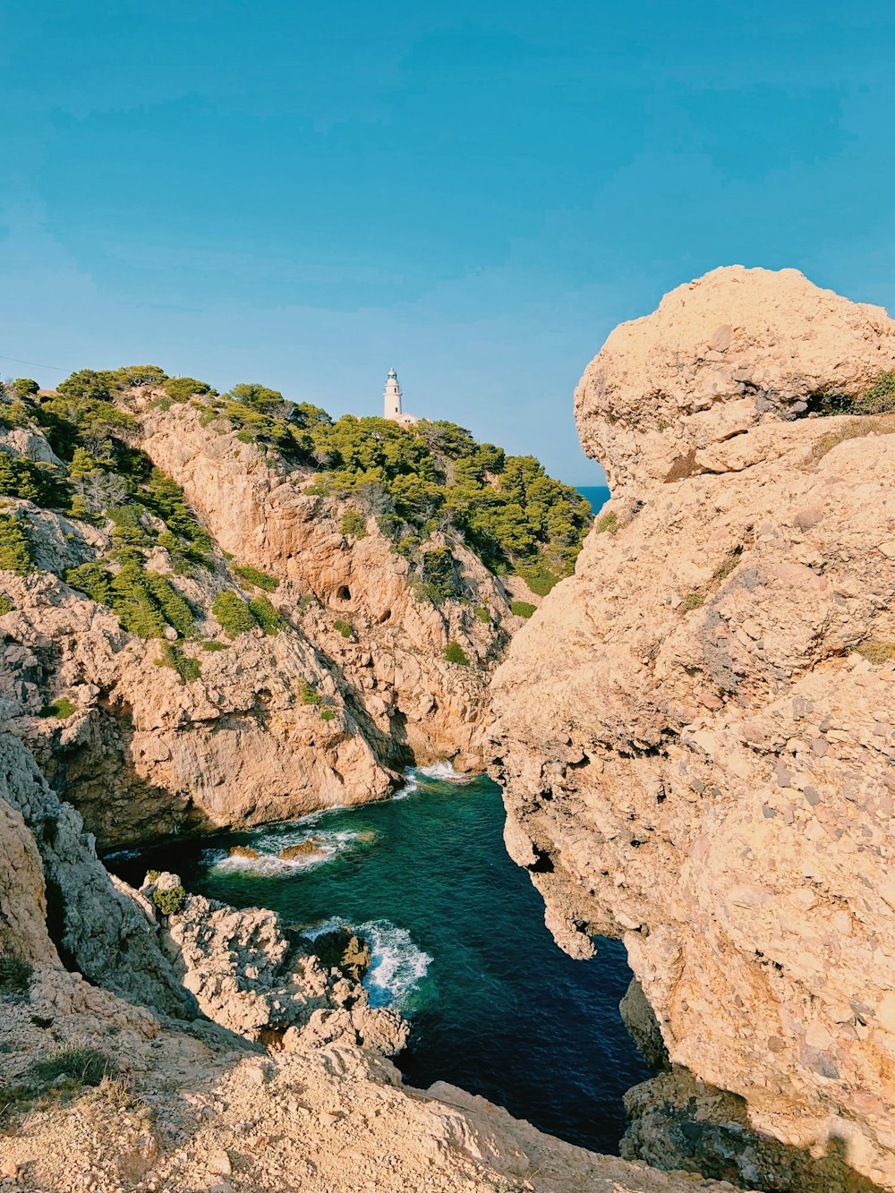 uma vista de uma costa rochosa com um farol à distância