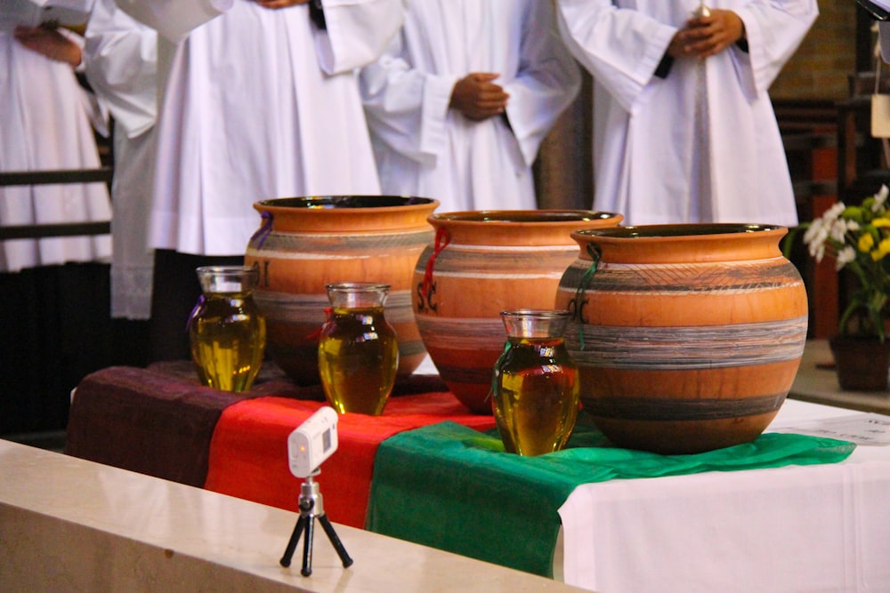 a group of people standing around a table with vases on it