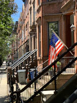 Agent handing keys to happy new homeowners in front of a classic NYC brownstone.
