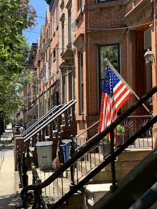 Charming brownstone townhouse with classic NYC stoop bathed in warm afternoon light.