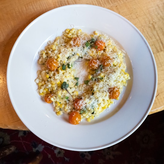 Close-up of a creamy risotto served in a rustic glass jar with fresh herbs on top.