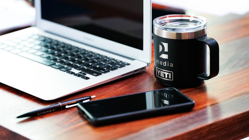 a laptop computer sitting next to a cup of coffee