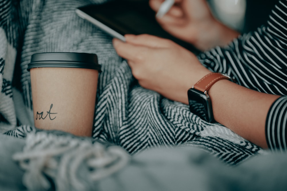 a woman holding a cup of coffee and a tablet