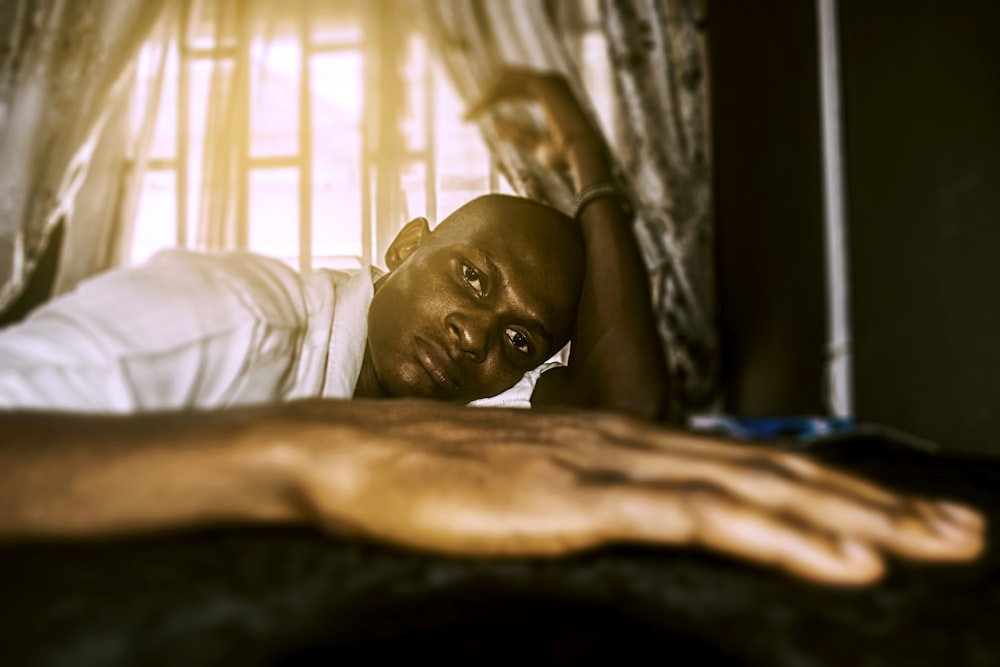 Un uomo sdraiato sopra un letto vicino a una finestra