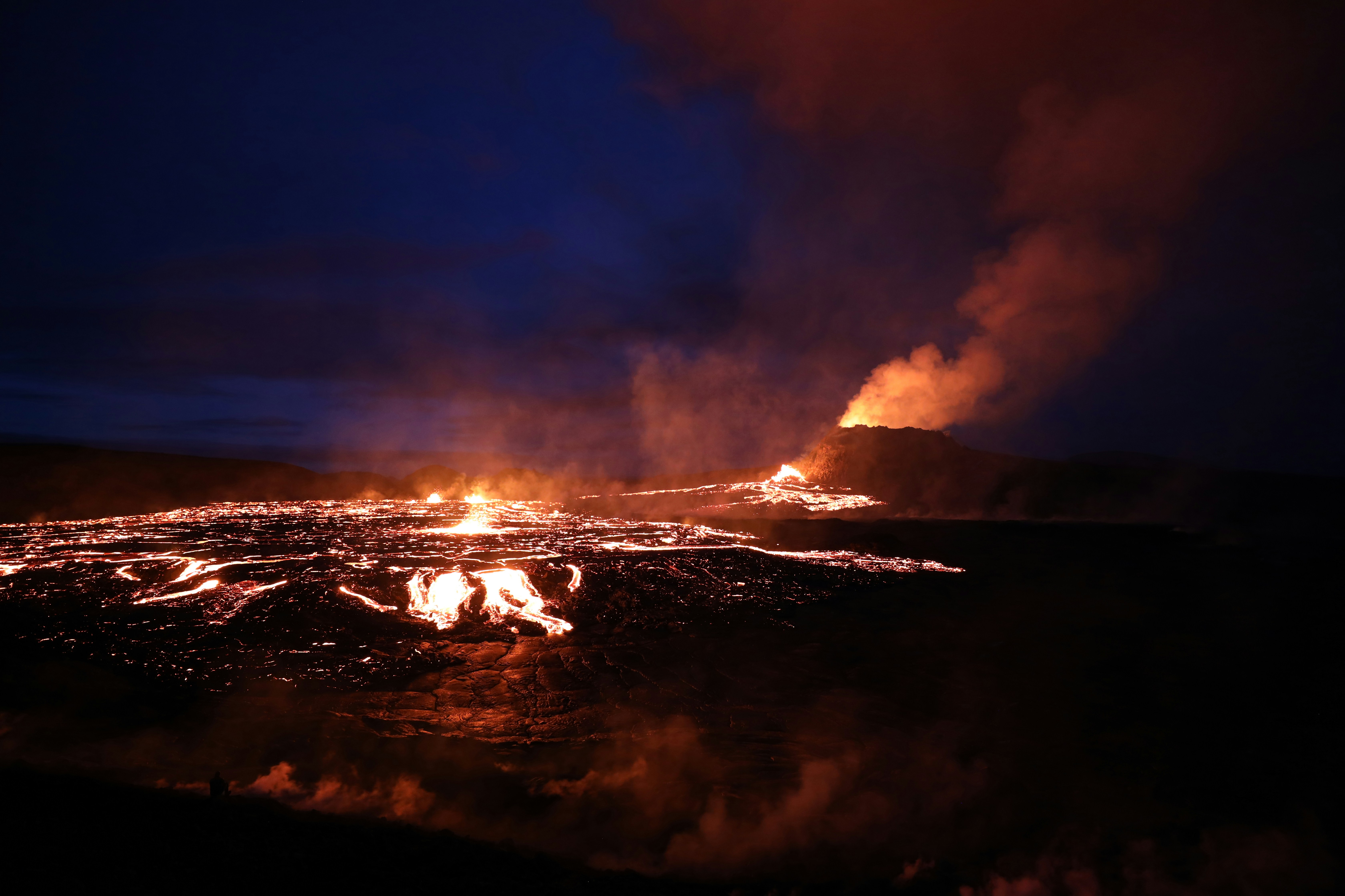 a group of people standing around a fire, The volcanic eruption at Geldingadalir, Fagradalsfjall.