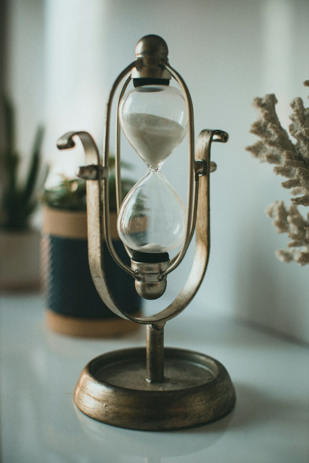 an hourglass sitting on top of a table next to a potted plant