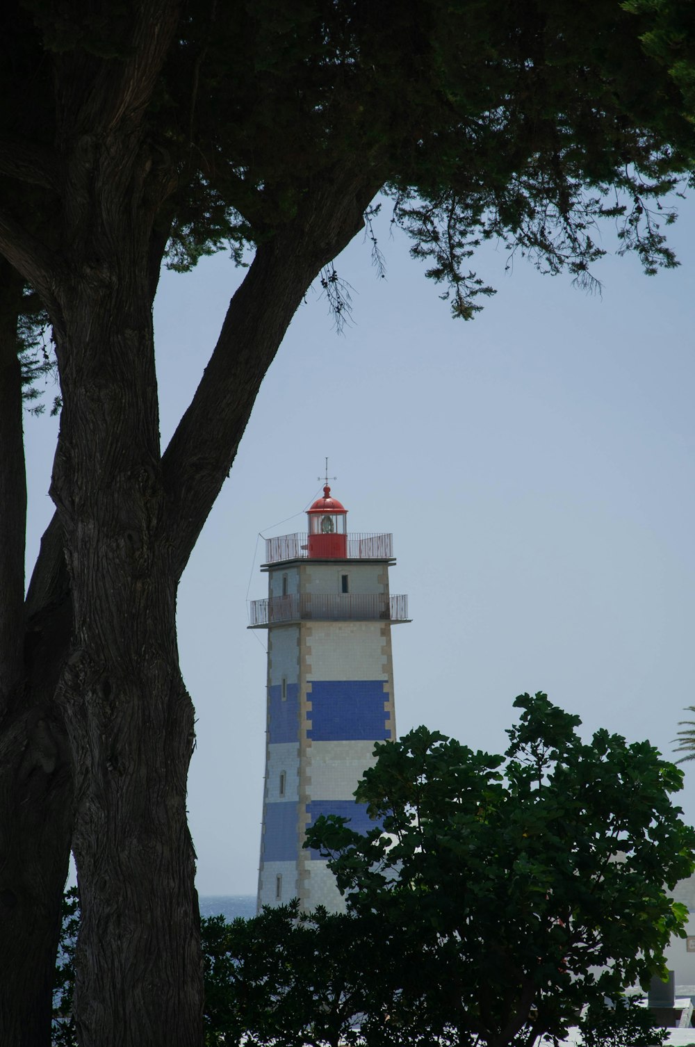 a tall light house sitting next to a tree