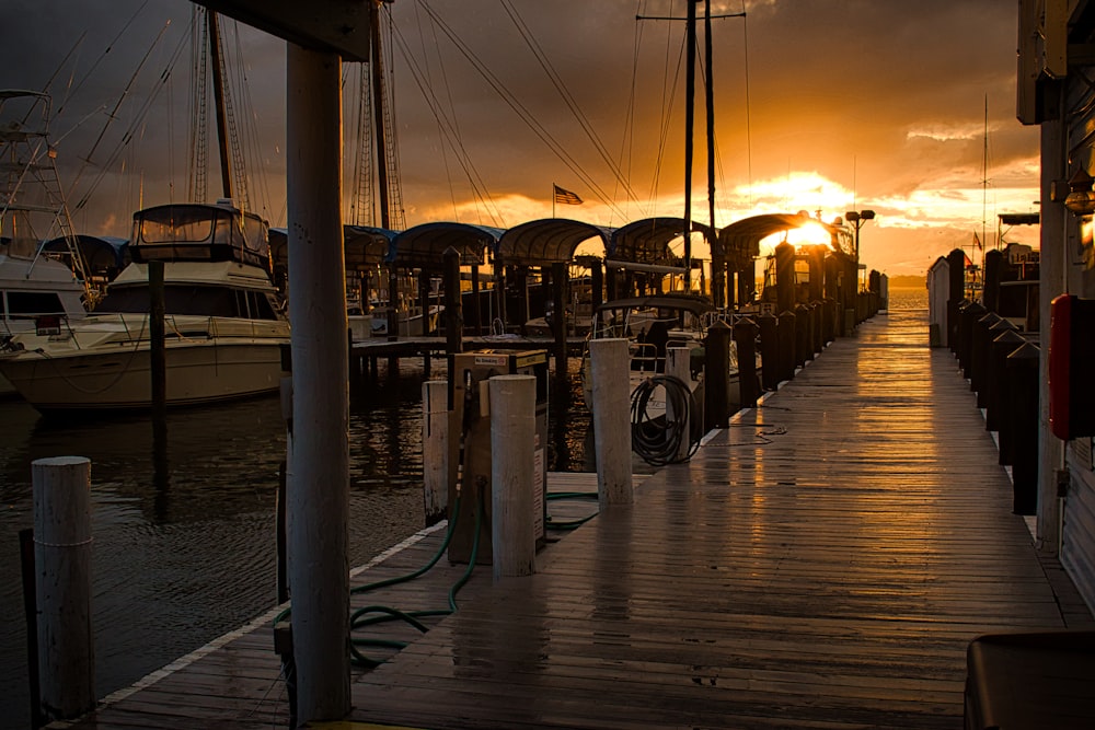 the sun is setting over a dock with boats