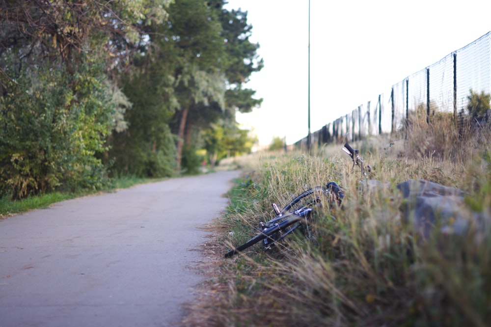 a bike laying on the side of a road next to a fence