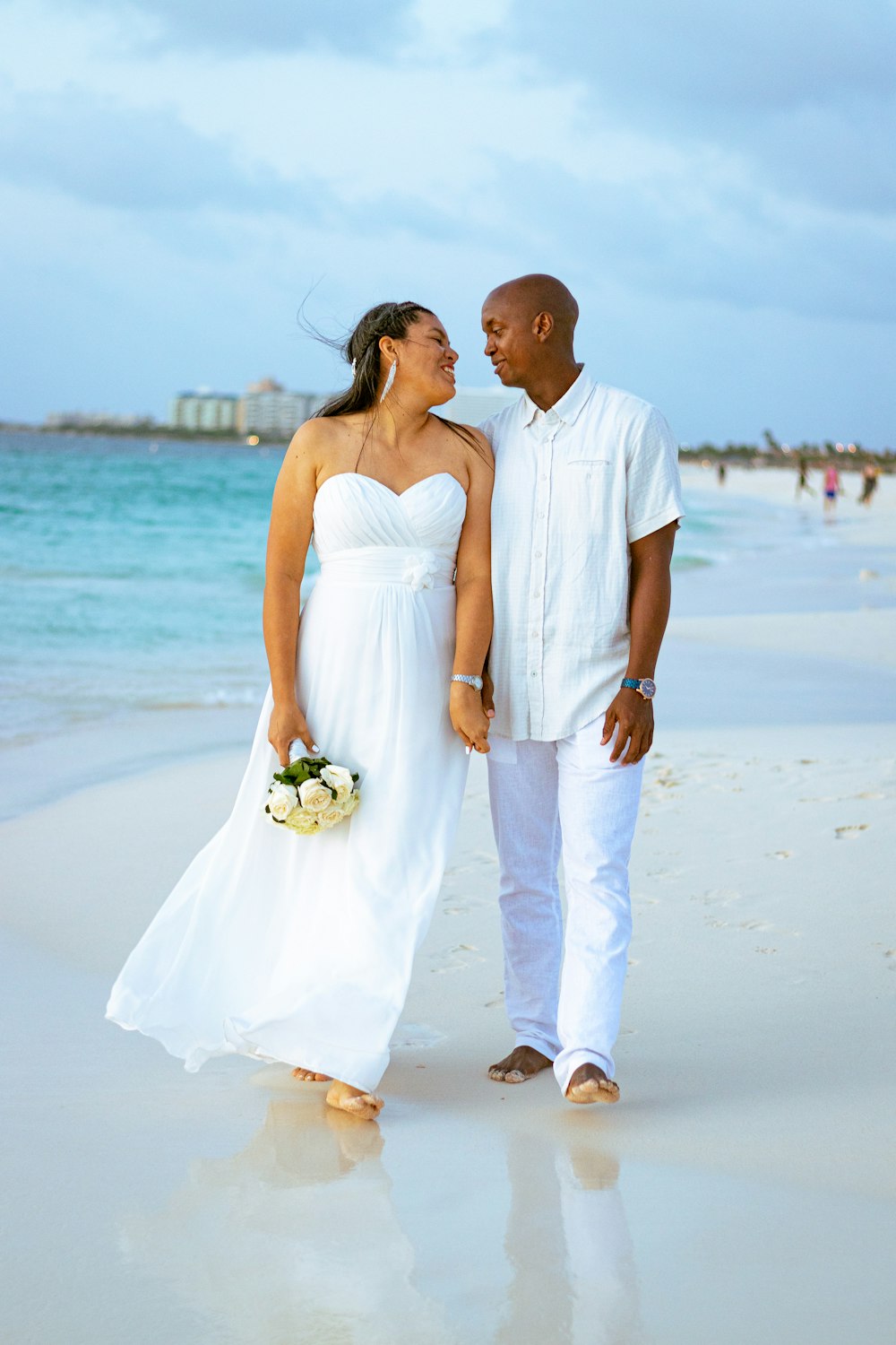 a man and woman standing on a beach next to the ocean