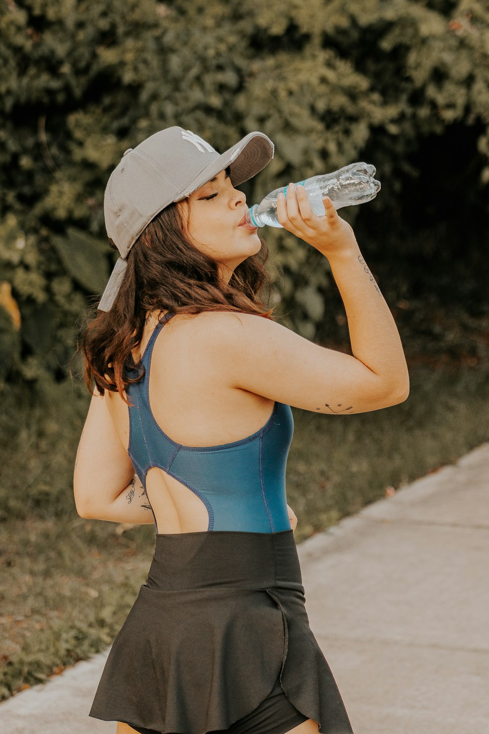 a woman with a hat drinking from a water bottle