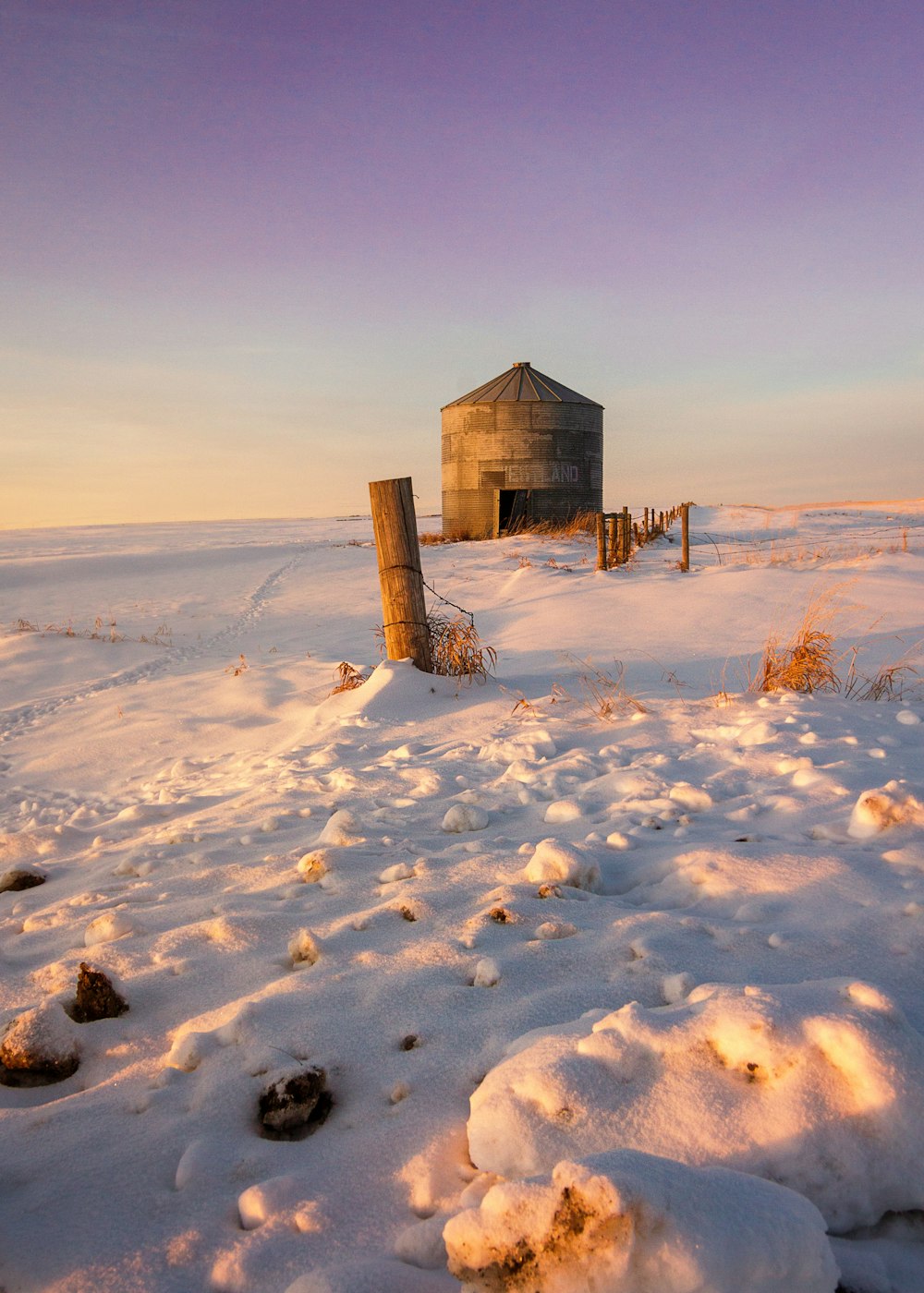 a barn in the middle of a snowy field