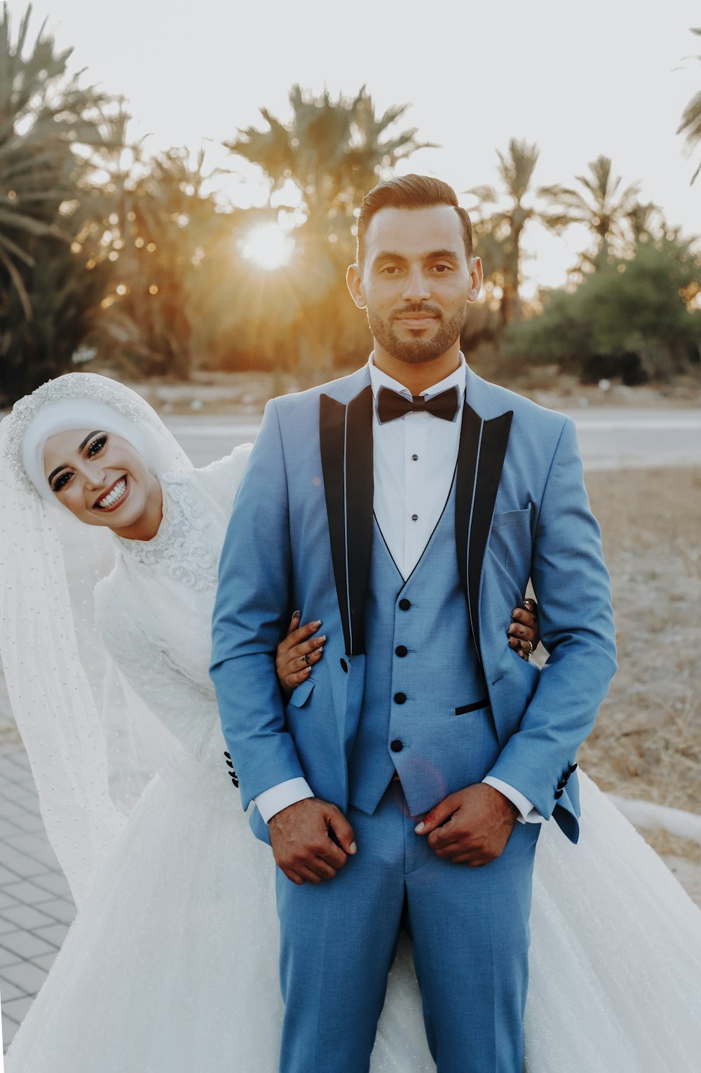 a bride and groom pose for a photo in front of palm trees