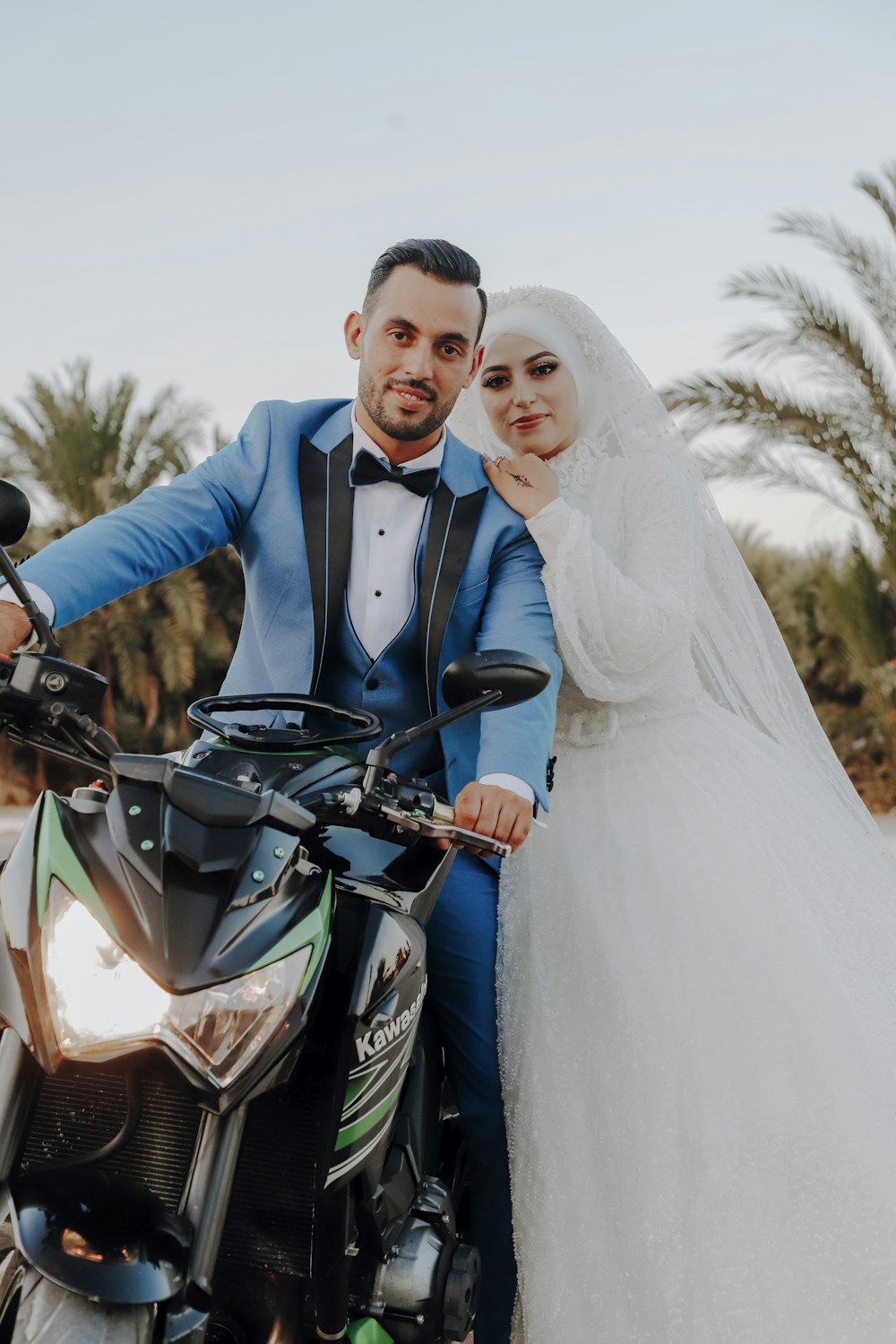a bride and groom pose on a motorcycle