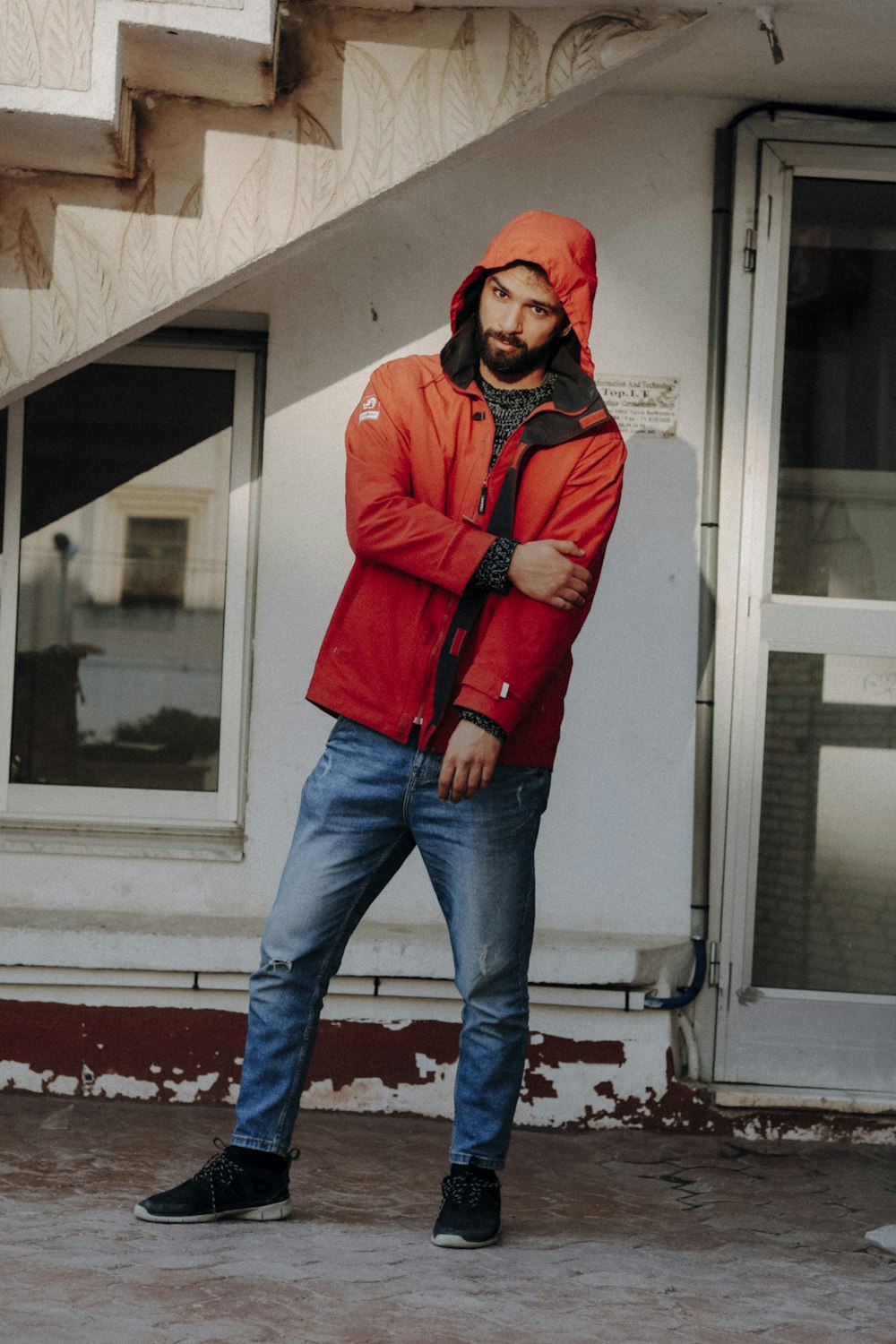 a man in a red jacket standing in front of a building