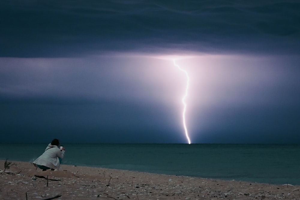 a bird standing on a beach under a lightning