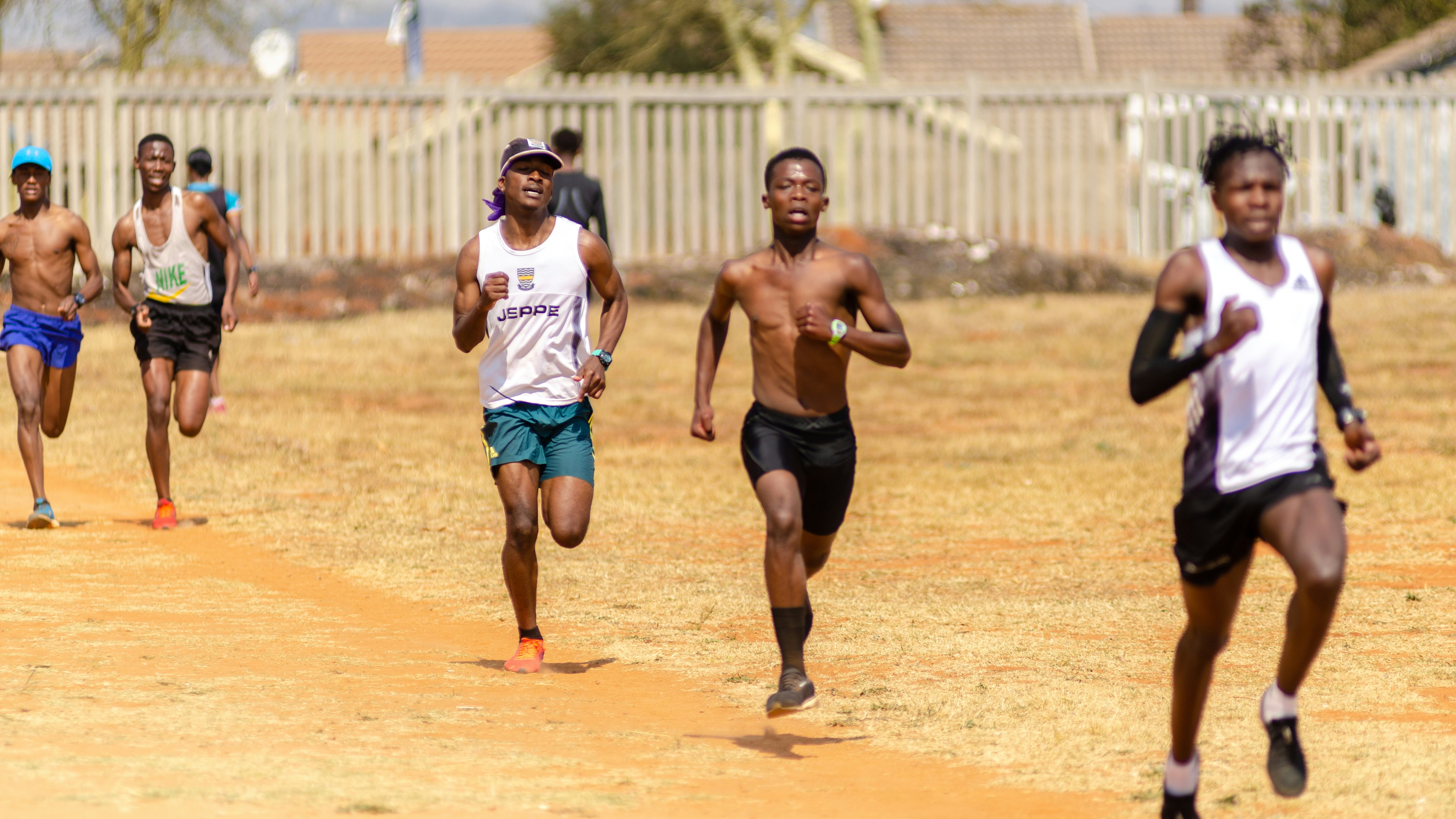 a group of men running down a dirt road
