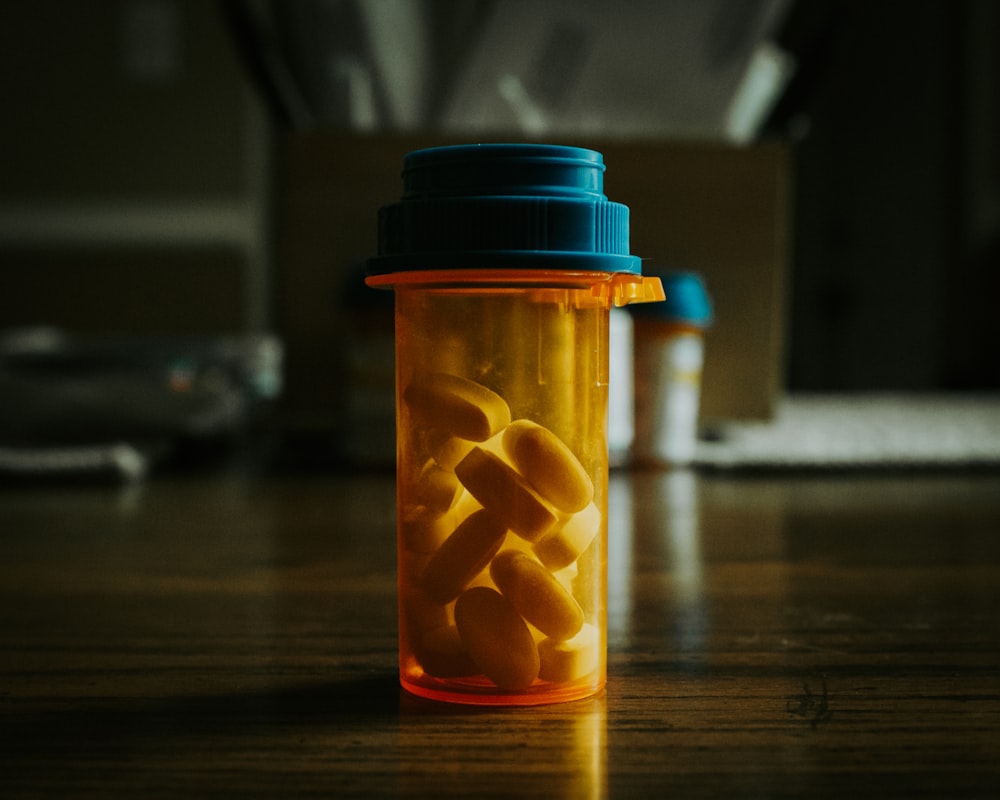 a bottle filled with pills sitting on top of a wooden table