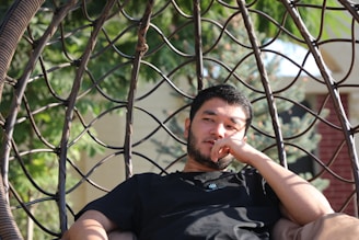 a man sitting in a hammock with his finger in his mouth