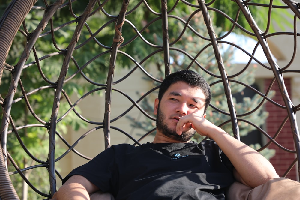 a man sitting in a hammock with his finger in his mouth