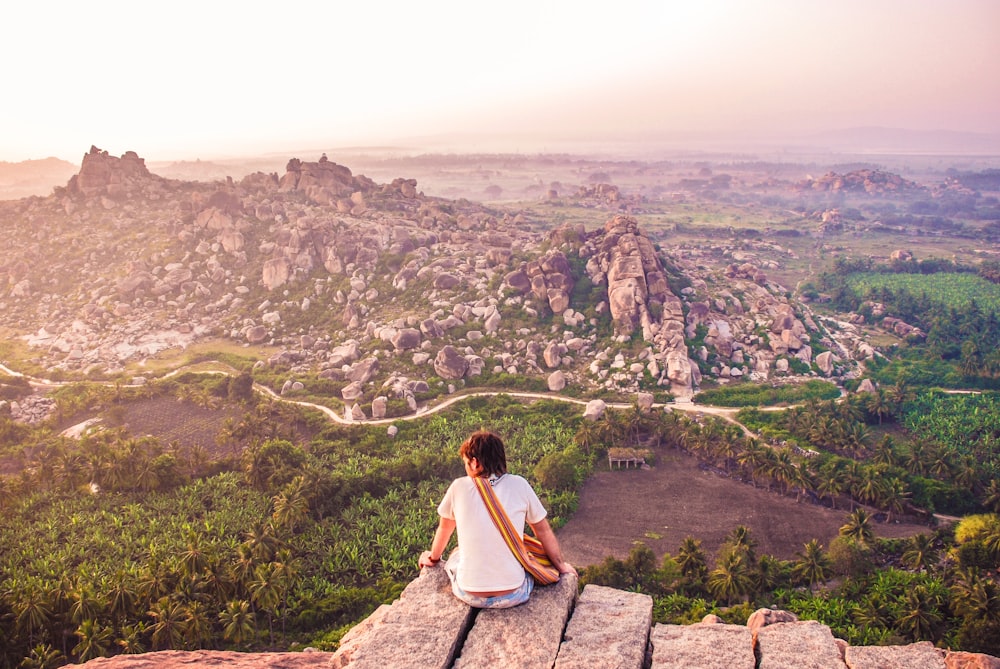 a person sitting on a rock overlooking a valley