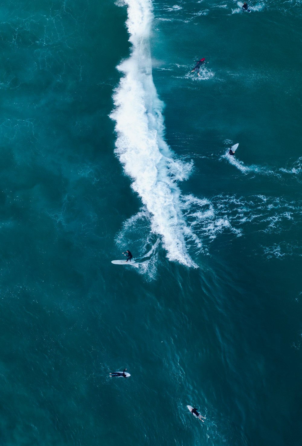 a group of people riding surfboards on top of a wave