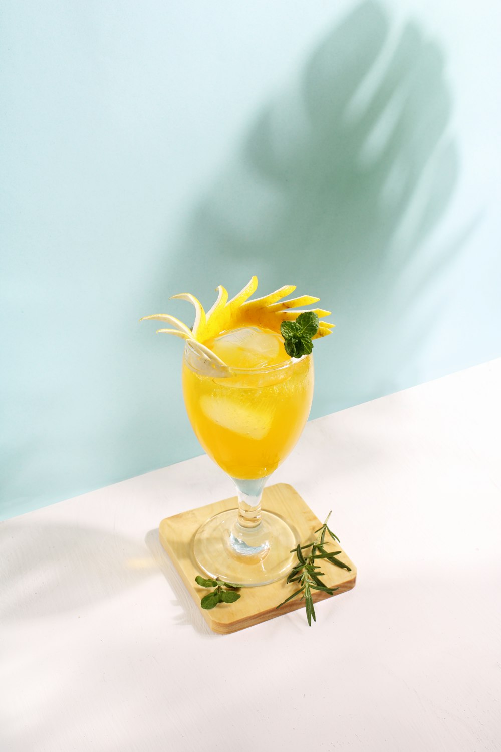 a glass of lemonade with a garnish on a coaster