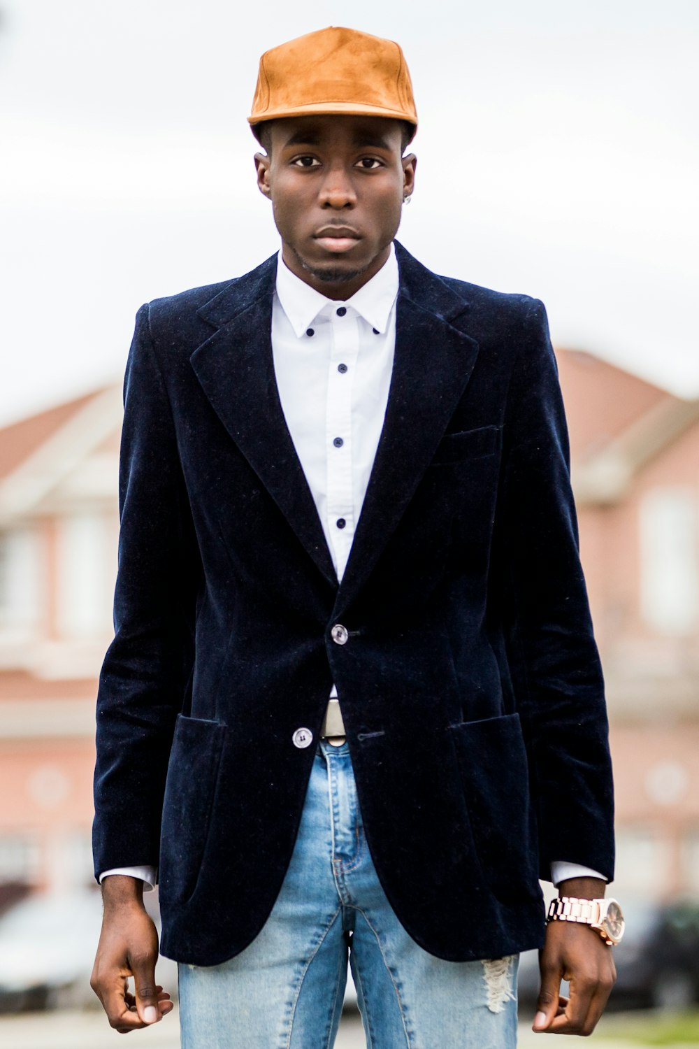 a man in a suit and hat standing in front of a building