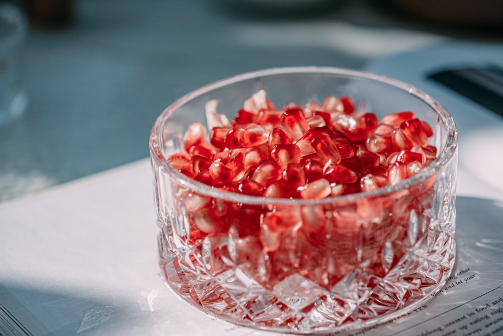 a glass bowl filled with pomegranates on top of a table