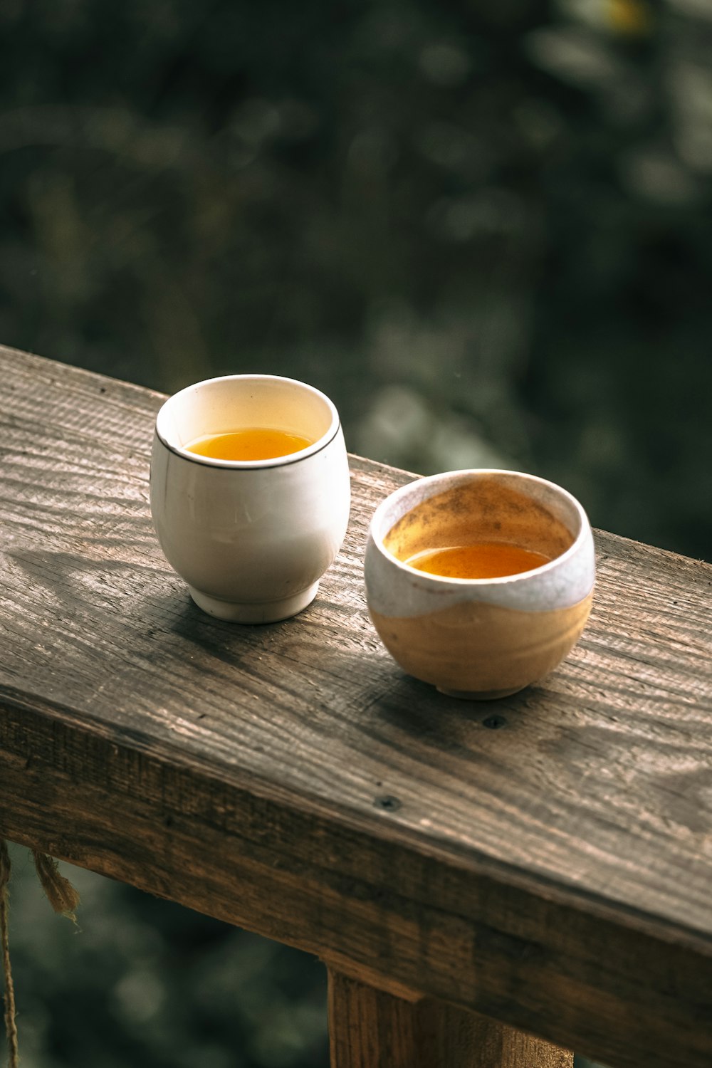 two bowls of tea sit on a wooden table