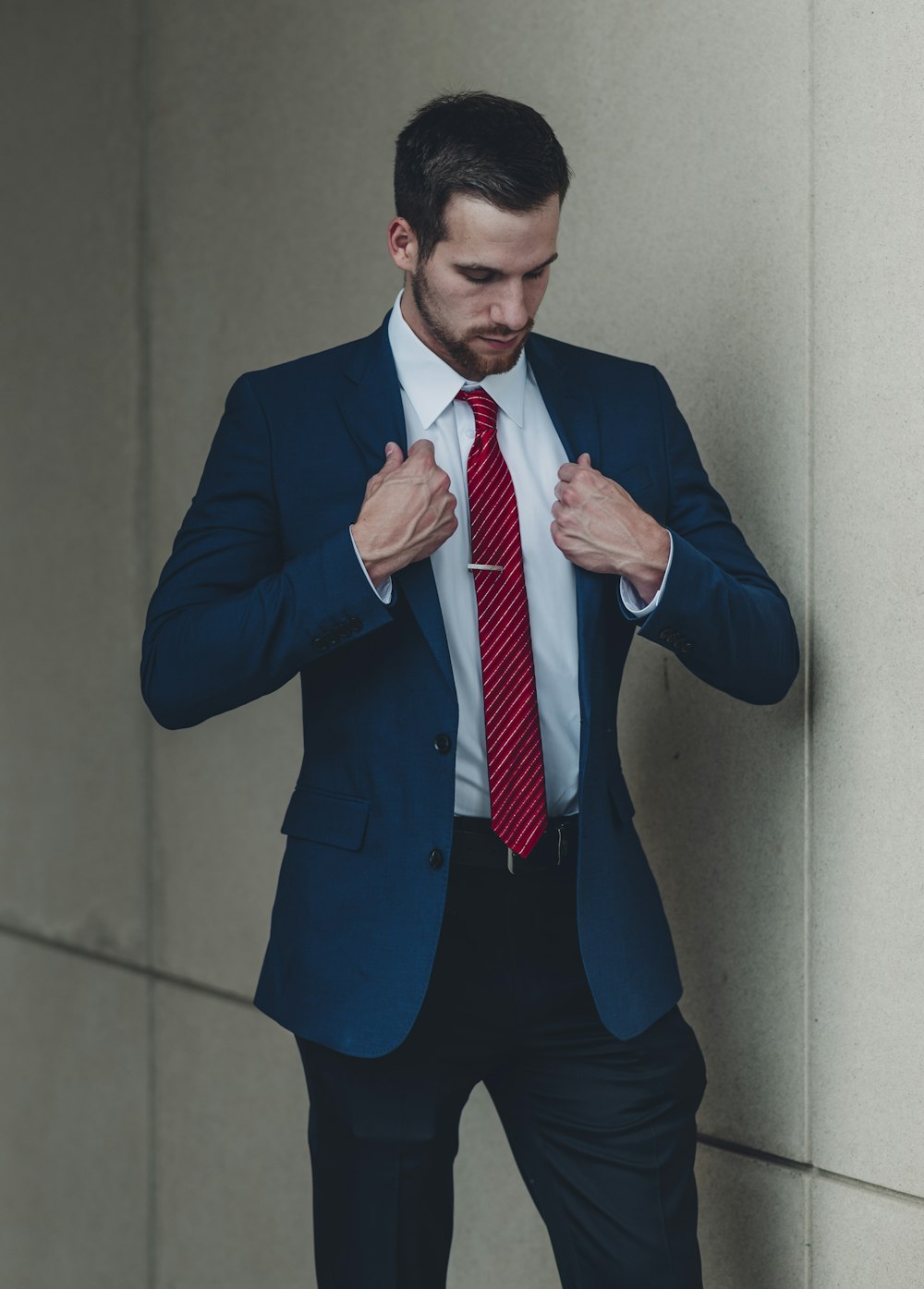 Ein Mann in Anzug und roter Krawatte bindet seine Krawatte