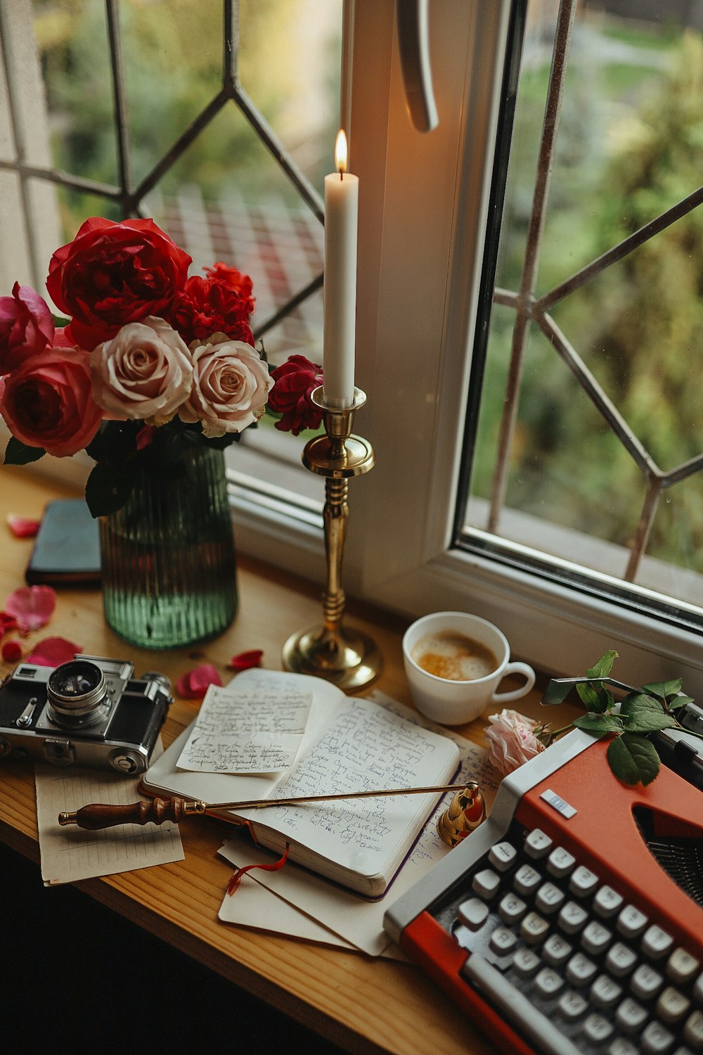 a desk with a typewriter, a cup of coffee, a candle, and