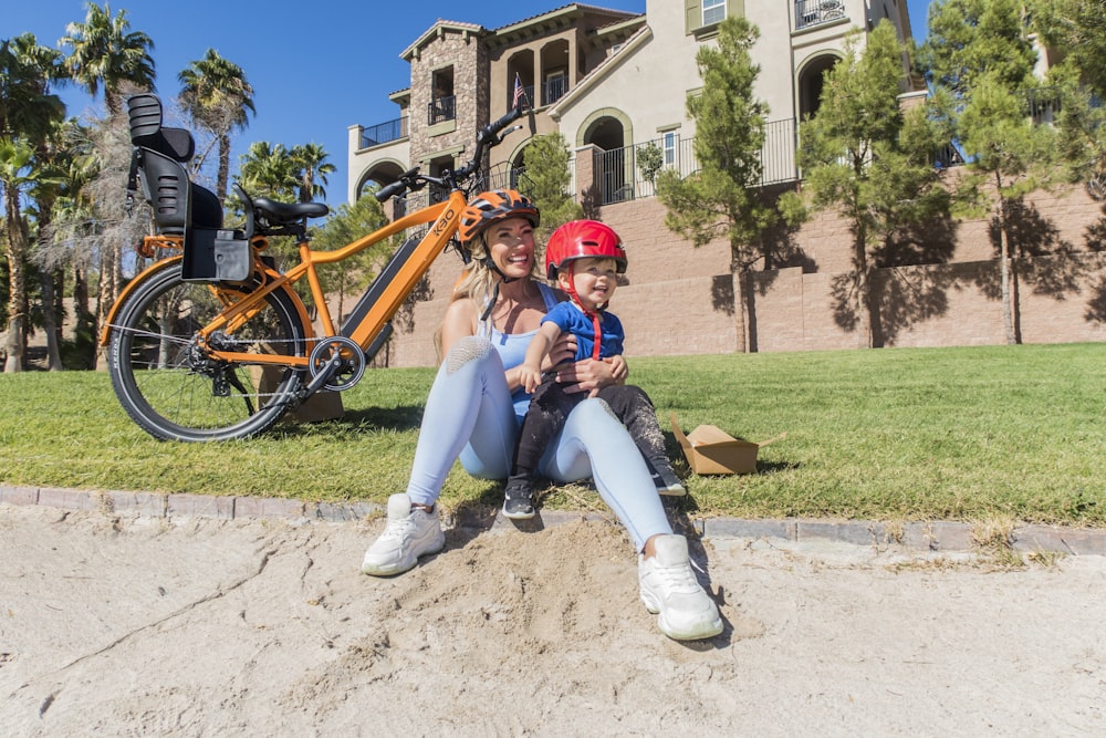 a man and a woman sitting on the ground next to a bike