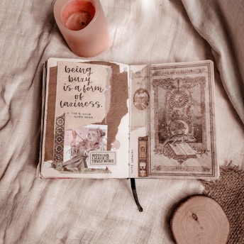 A cozy nighttime crafting setup with a scrapbook, colorful papers, and a cup of tea on a wooden table.