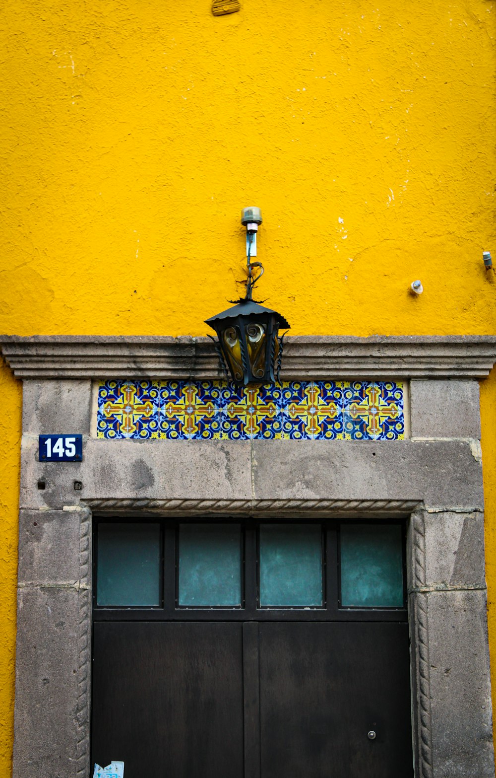 a yellow building with a black door and a clock