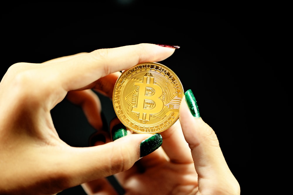 a close up of a person holding a gold bit coin