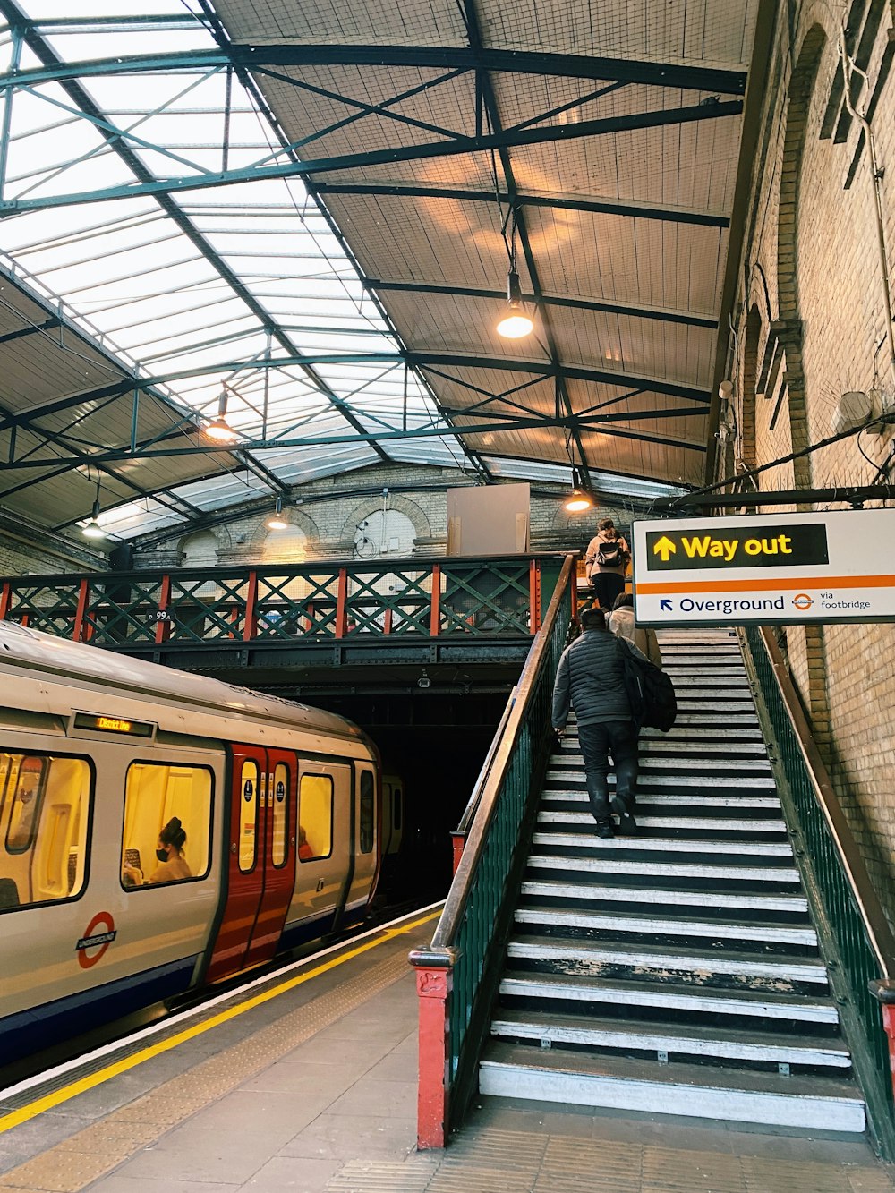 a man walking up a set of stairs next to a train