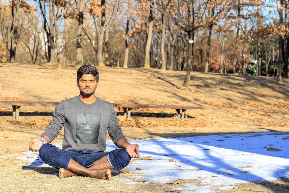 a man sitting in the middle of a park doing yoga