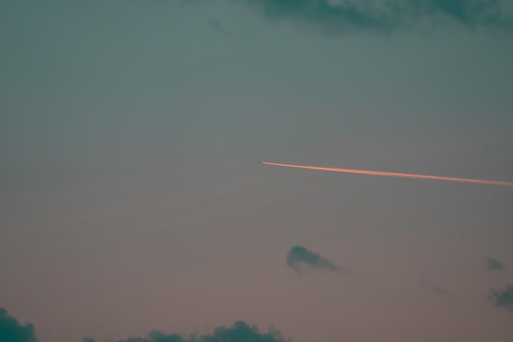 an airplane is flying in the sky at dusk