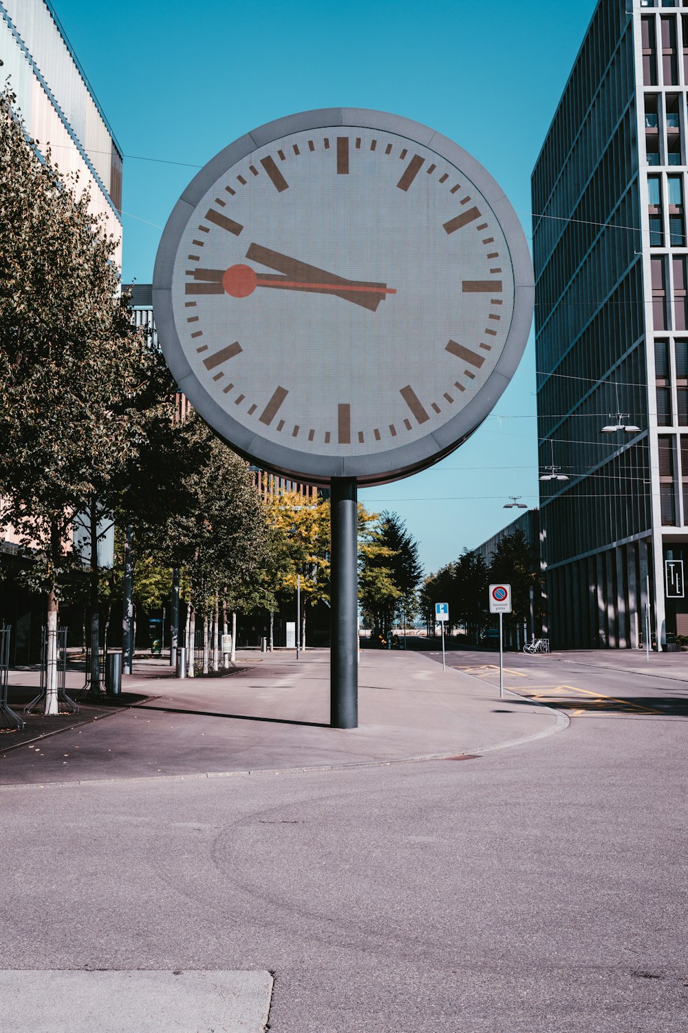um grande relógio em um poste no meio de uma rua
