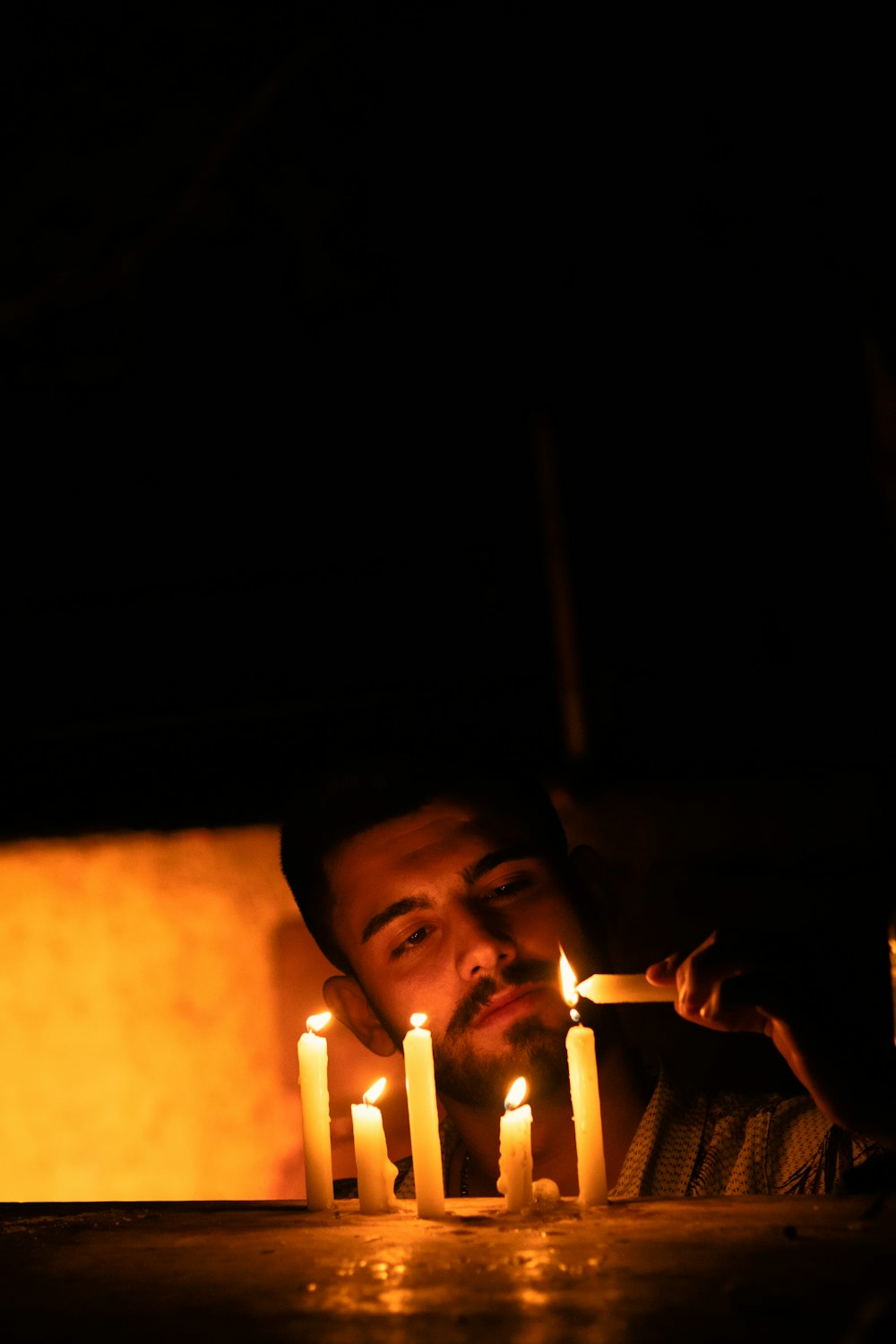 a man sitting at a table with a bunch of candles in front of him