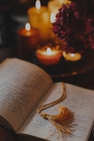 Close-up of an open book with handwritten notes and a glowing candle beside it, evoking a sense of quiet reflection.