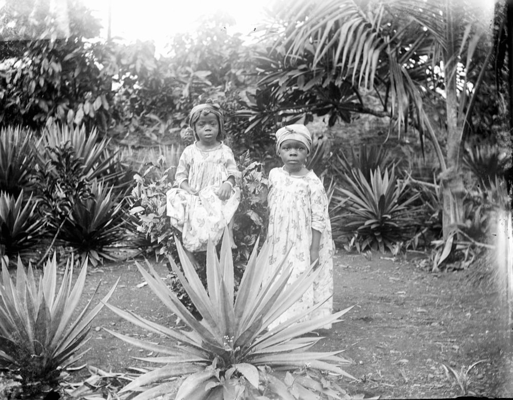 two young girls standing next to each other in a garden